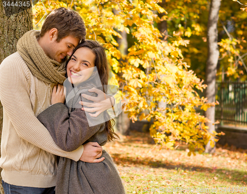 Image of smiling couple hugging over autumn background