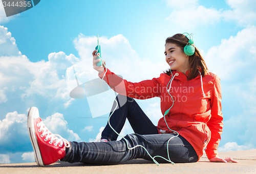 Image of happy young woman with smartphone and headphones