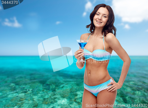 Image of happy young woman in swimsuit drinking cocktail