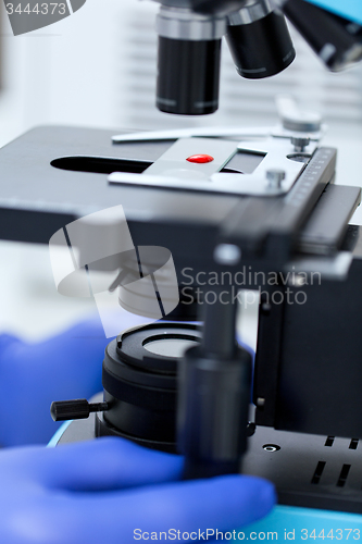 Image of close up of hands with microscope and blood sample