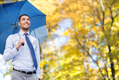 Image of businessman with umbrella over autumn background
