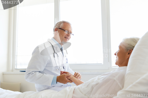 Image of doctor checking senior woman pulse at hospital