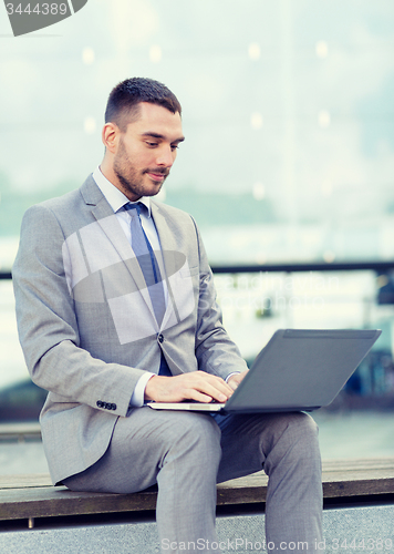 Image of businessman working with laptop outdoors