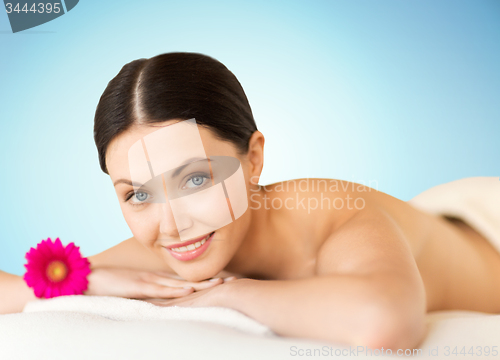 Image of happy beautiful woman lying on massage desk at spa