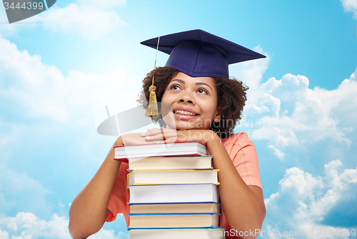 Image of happy african bachelor girl with books over sky