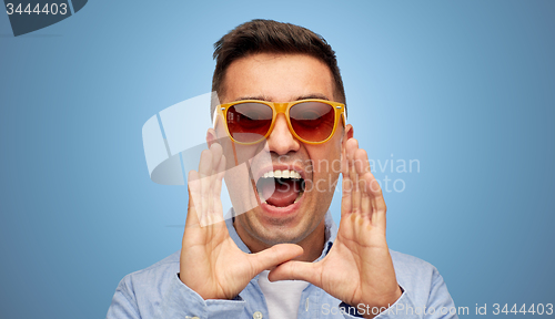 Image of face of angry shouting man in shirt and sunglasses