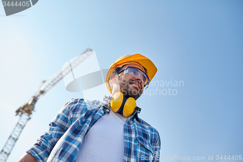 Image of smiling builder with hardhat and headphones