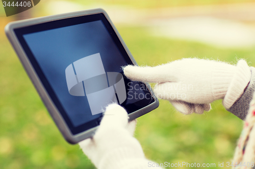 Image of hands in autumn gloves holding tablet pc outdoors