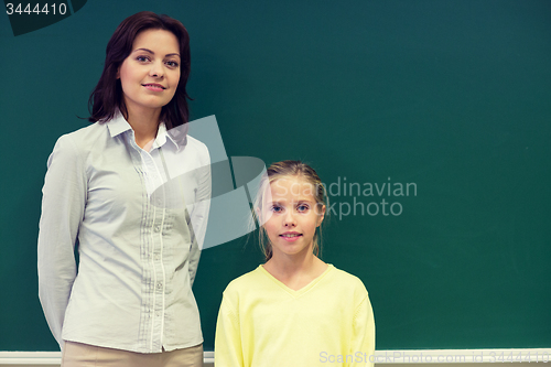 Image of little school girl with teacher at blackboard