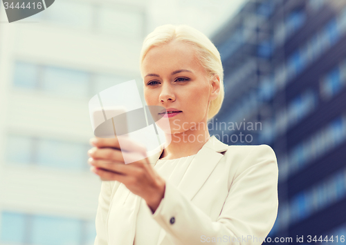 Image of serious businesswoman with smartphone outdoors