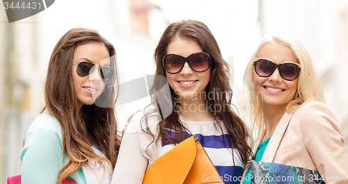 Image of three smiling women with bags in the city