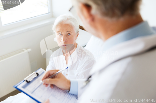 Image of senior woman and doctor with clipboard at hospital