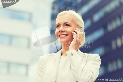 Image of smiling businesswoman with smartphone outdoors