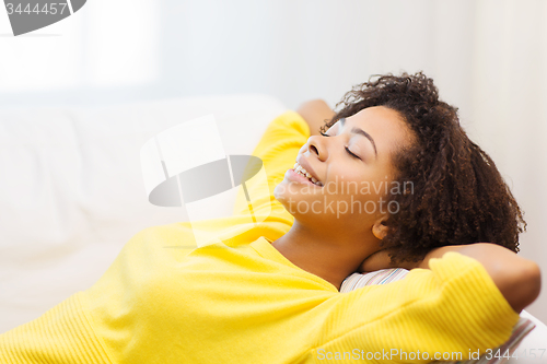 Image of happy african young woman relaxing at home