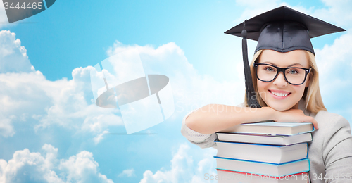 Image of student in trencher cap with books over blue sky