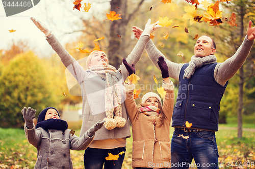 Image of happy family playing with autumn leaves in park