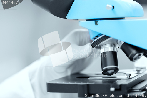 Image of close up of scientist hand setting microscope