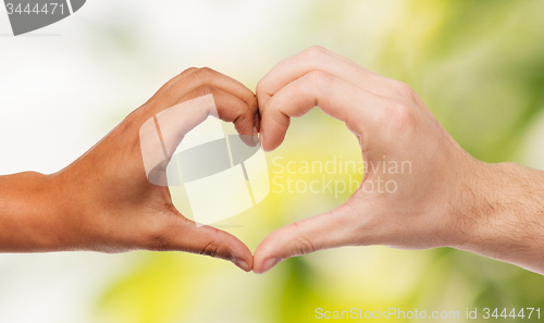 Image of woman and man hands showing heart shape