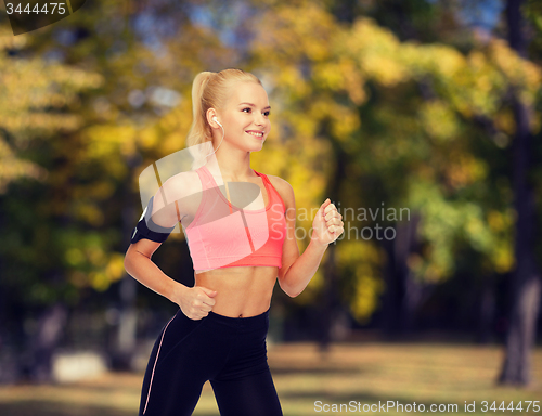 Image of sporty woman running with smartphone and earphones