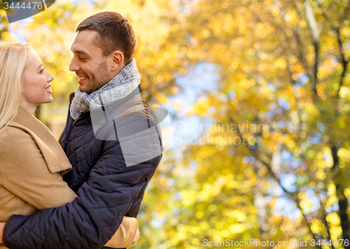 Image of smiling couple hugging over autumn background