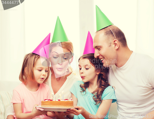 Image of smiling family with two kids in hats with cake