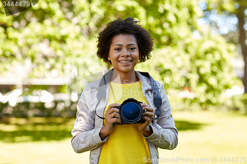 Image of happy african woman with digital camera in park