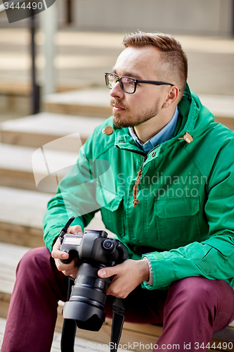 Image of young hipster man with digital camera in city