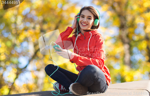Image of happy young woman with smartphone and headphones