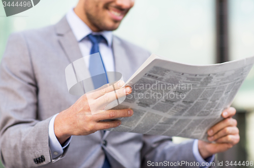 Image of close up of smiling businessman reading newspaper