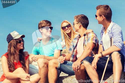 Image of group of smiling friends sitting on city street