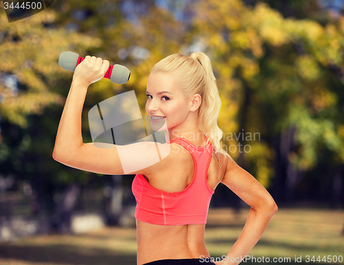 Image of young sporty woman with light dumbbell