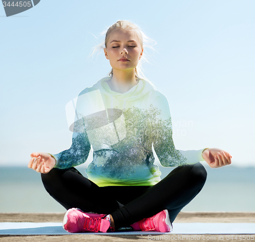 Image of happy young woman doing yoga outdoors