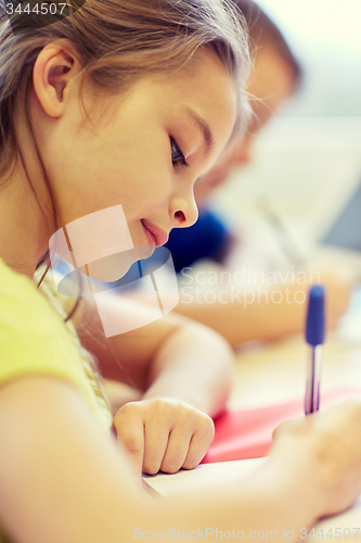 Image of close up of school kids writing test in classroom