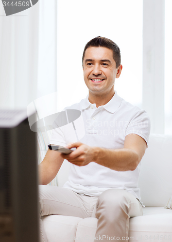 Image of smiling man with remote control watching tv