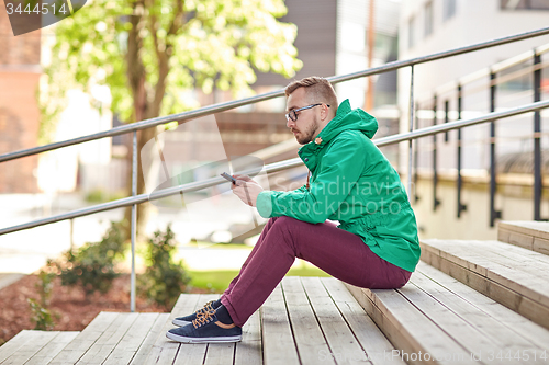 Image of young hipster man with smartphone in city