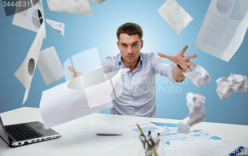 Image of angry businessman throwing papers in office