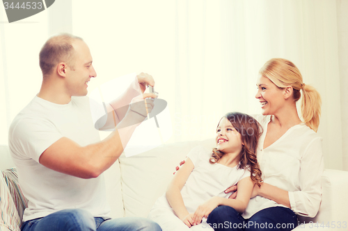 Image of happy father taking picture of mother and daughter