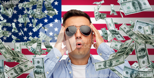 Image of surprised man under money rain over american flag