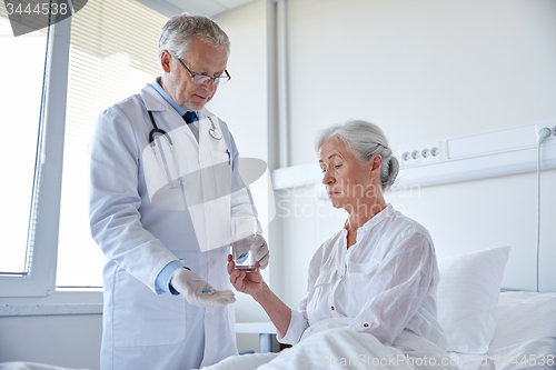 Image of doctor giving medicine to senior woman at hospital