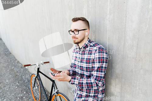 Image of hipster man in earphones with smartphone and bike