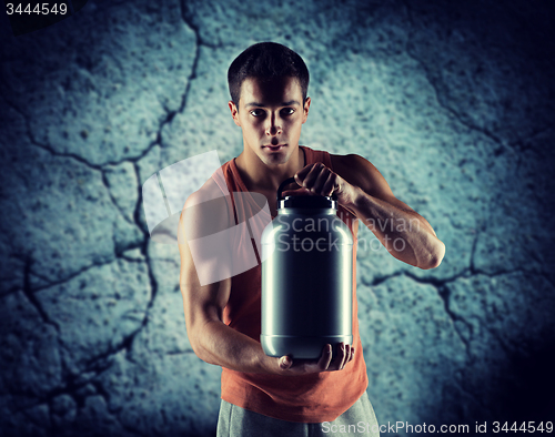 Image of young male bodybuilder holding jar with protein