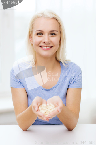 Image of happy woman holding pills or capsules at home