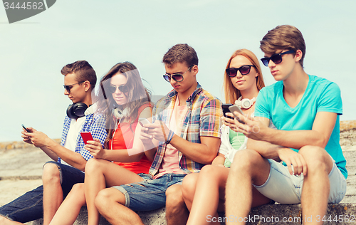 Image of group of friends with smartphones outdoors