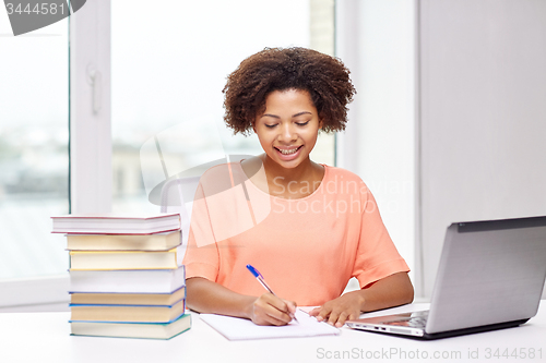 Image of happy african american woman with laptop at home