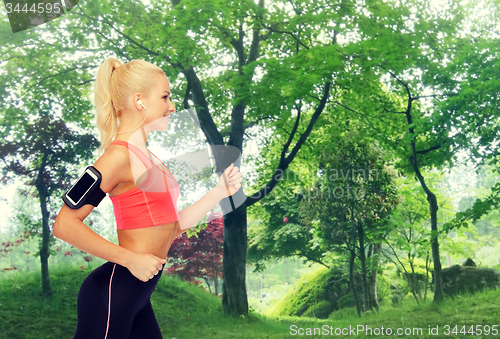 Image of sporty woman running with smartphone and earphones