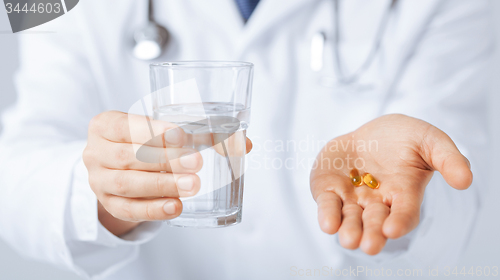 Image of doctor hands giving capsule and glass of water