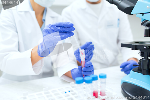 Image of close up of scientists filling test tube in lab