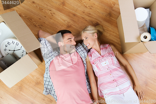 Image of happy couple lying on floor among cardboard boxes