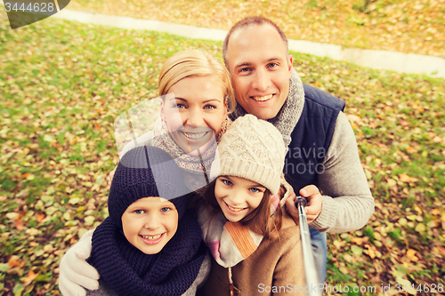 Image of happy family with selfie stick in autumn park