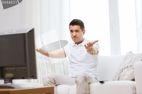 Image of disappointed man watching tv at home